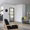 Een huiskamer met een staal look deur op de achtergrond en een fauteuil op de voorgrond.