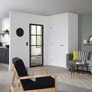 Een huiskamer met een staal look deur op de achtergrond en een fauteuil op de voorgrond.