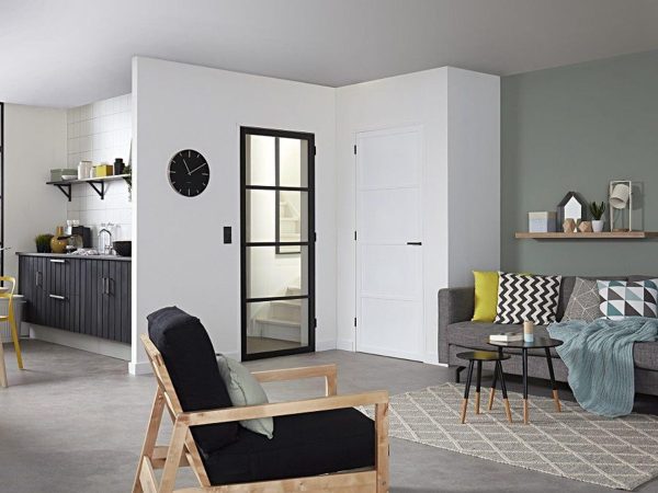 Een huiskamer met een staal look deur op de achtergrond en een fauteuil op de voorgrond.