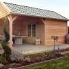 Schuur met overkapping in groene tuin. De schuur is bekleed met onbehandelde Douglas Zweeds rabatdelen, welke te koop zijn bij Bouwie