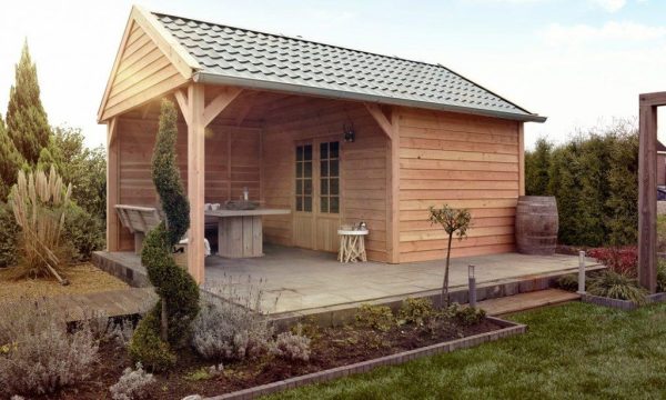 Schuur met overkapping in groene tuin. De schuur is bekleed met onbehandelde Douglas Zweeds rabatdelen, welke te koop zijn bij Bouwie