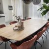 Eetkamer met massief eiken deens ovaal tafelblad en zwarte matrixpoot. Op de tafel staat wat decoratie en aan de tafel staan 8 kuipstoelen in koper kleur